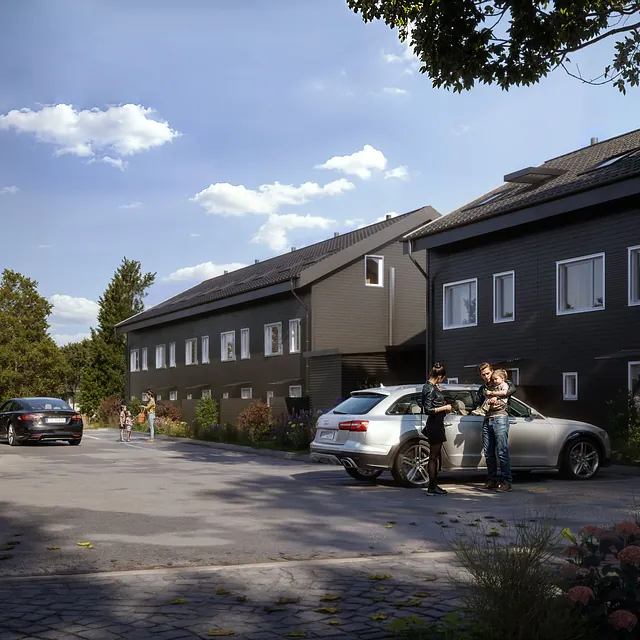 Moderne rekkehus fra utsiden med parkerte bilder og småbarnsfamilier foran